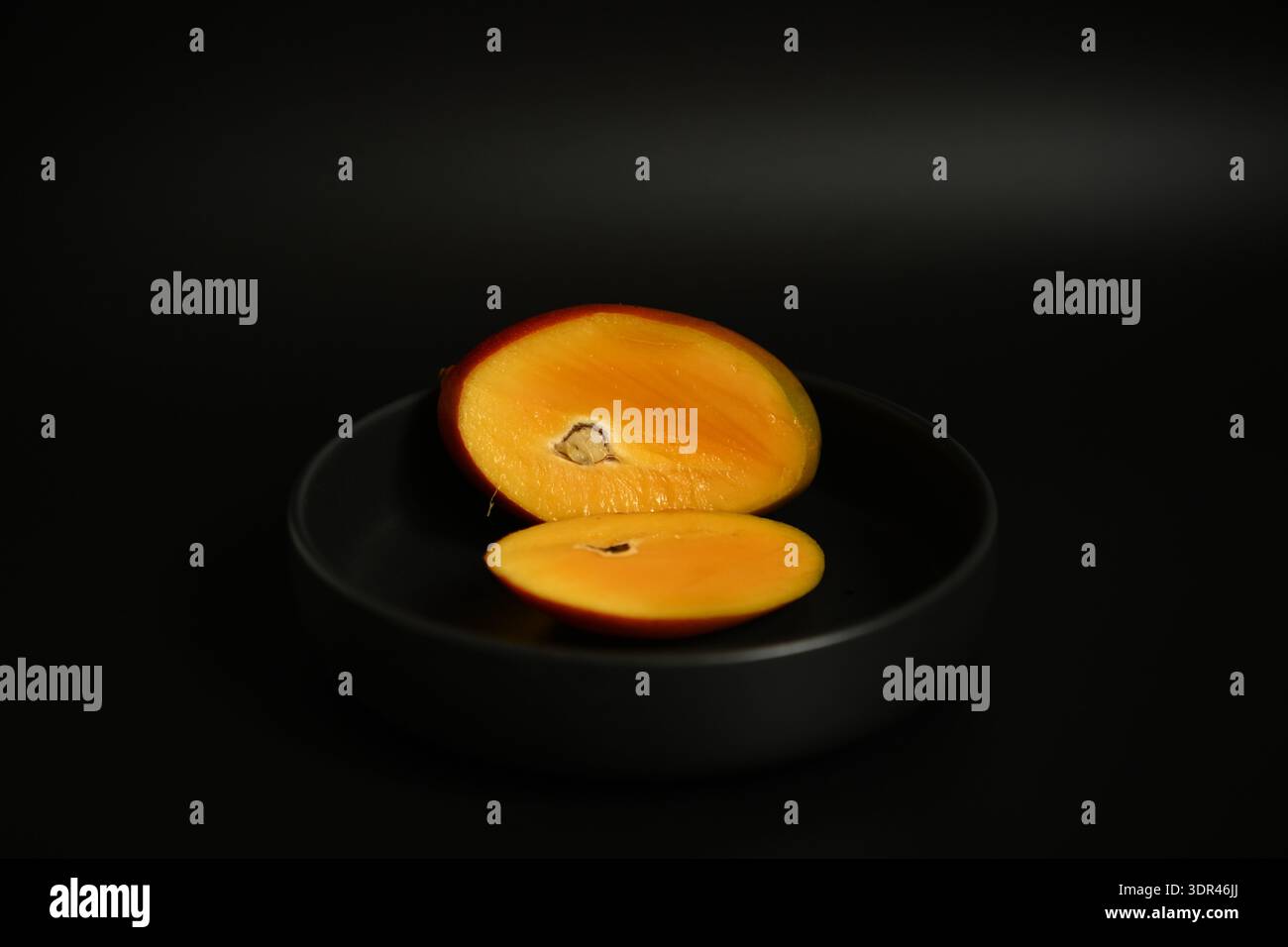 Frisch geschnittene Mango in Glasschale auf dunklem Hintergrund, zuckerfreies Diätkonzept Stockfoto