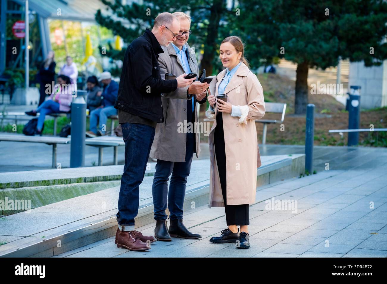 Business Lifestyle-Moment in der Stadt: Profis im mittleren Alter treffen sich im Freien, arbeiten mit Laptop und Telefon zusammen Stockfoto