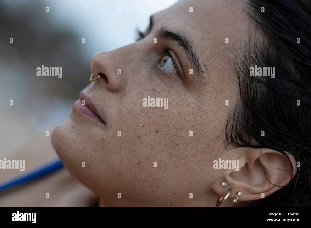 Das Gesicht der jungen Frau im Profil, das nach oben blickt, verloren in Gedanken und Nachsicht Stockfoto