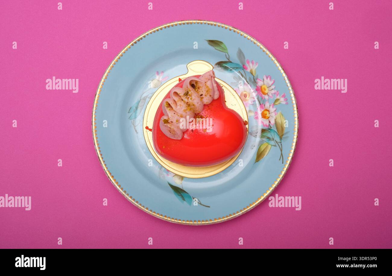 Erdbeer-Pistazien-Enremet-Kuchen auf Blumenteller auf rosa Hintergrund Stockfoto