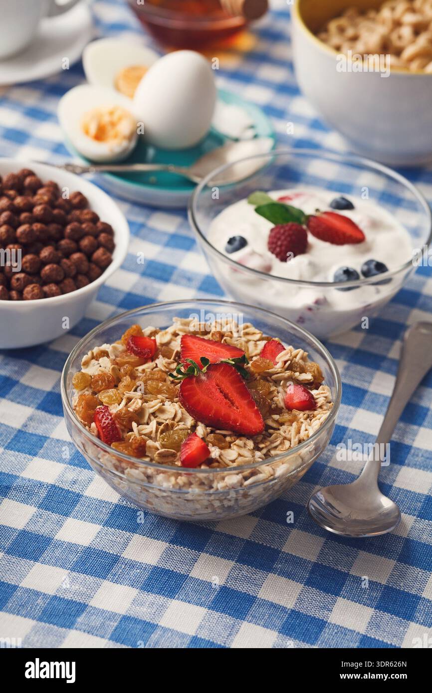 Frühstückskollektion mit Obst und Müsli auf einer karierten Tischdecke Stockfoto
