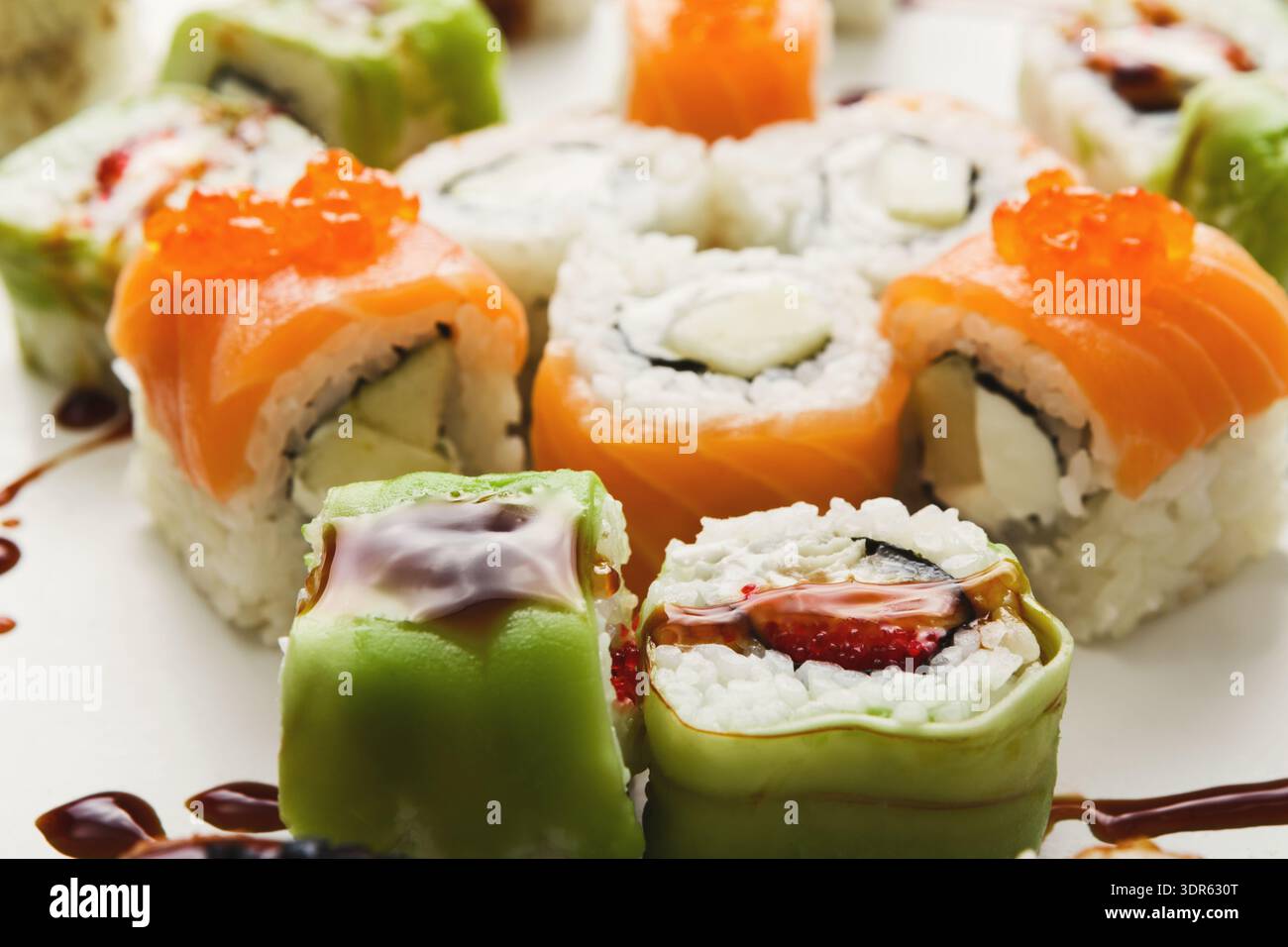 Sushi-Brötchen auf einem Teller mit verschiedenen Belägen und Saucen während einer Mahlzeit Stockfoto