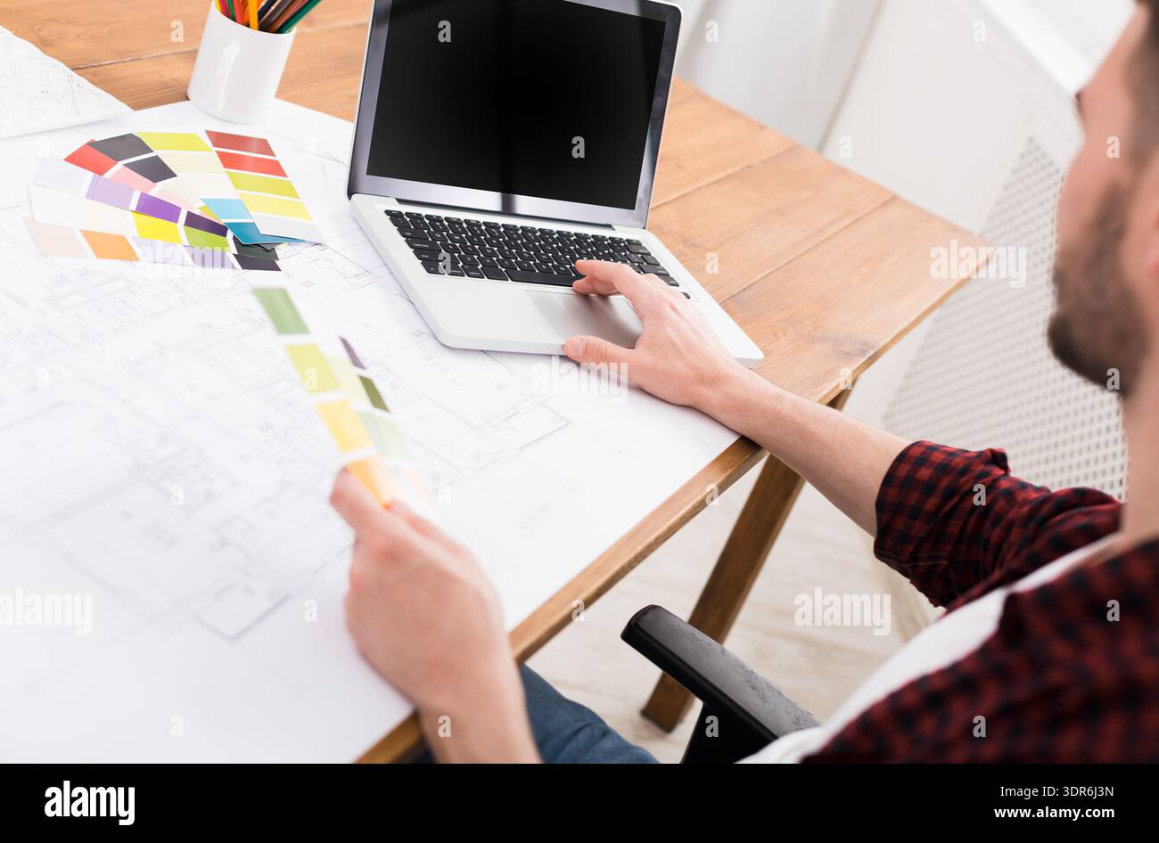 Designer arbeitet am Schreibtisch mit Laptop und Farbpalette in Bright Workspace Stockfoto
