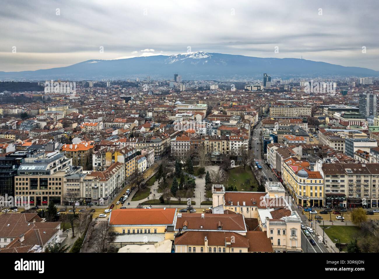 Panoramablick auf Sofia, Bulgarien, mit dichten roten Dächern und städtischen Straßen, die sich zum schneebedeckten Vitosha-Berg unter bedecktem Himmel erstrecken Stockfoto