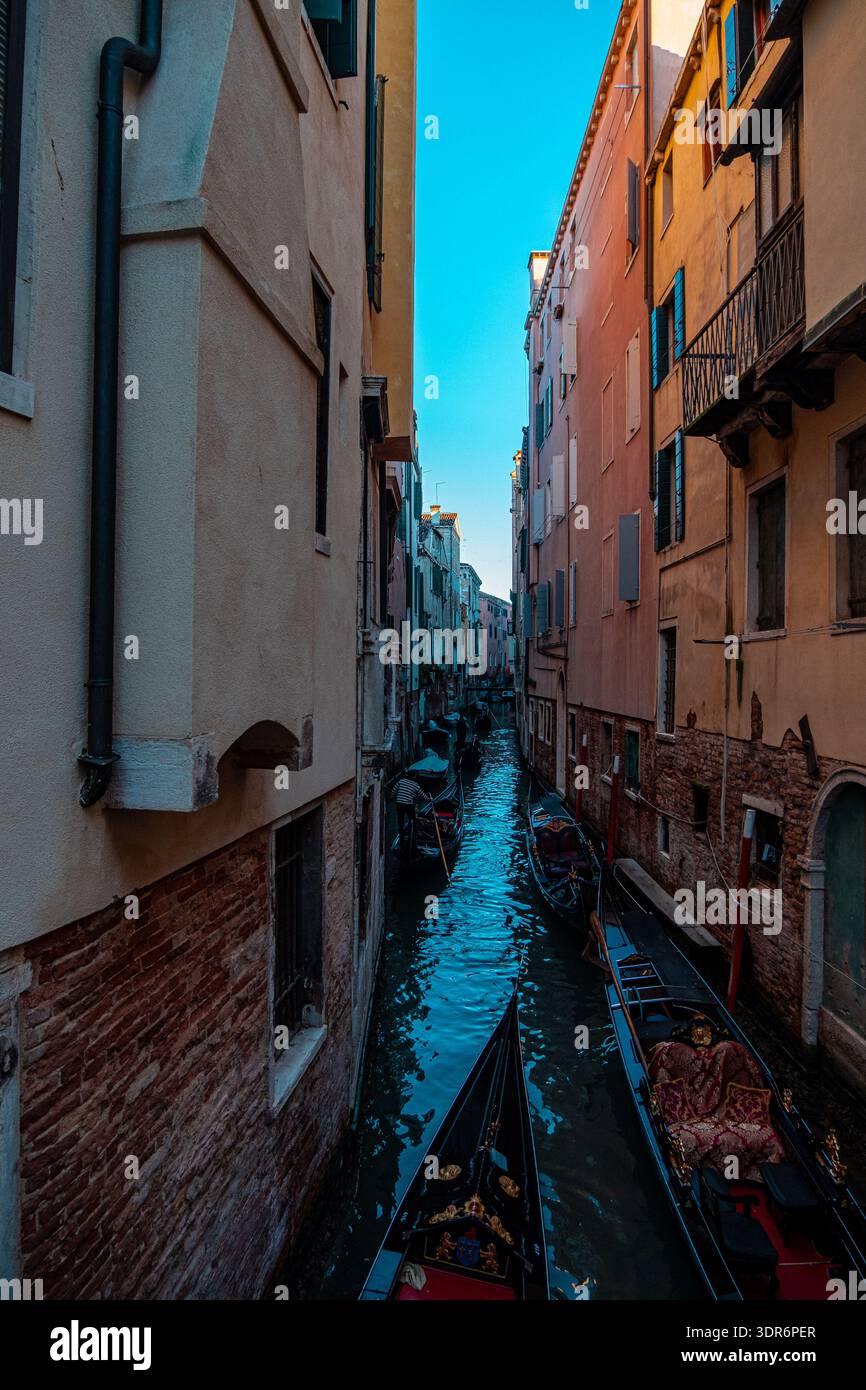 Venedig, Italien – 15. Februar 2026: Traditionelle Gondeln führen die Passagiere durch einen engen Kanal, der von historischen Gebäuden gesäumt ist. Stockfoto