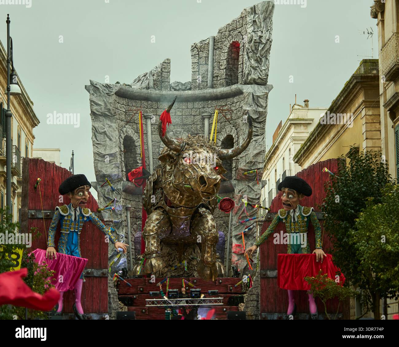 Großer Bulle aus Pappe mâché, umgeben von Matadoren und antiken griechischen Ruinen auf einem allegorischen Wagen für den 632. Karneval von Putignano, Apulien, Italien. Stockfoto