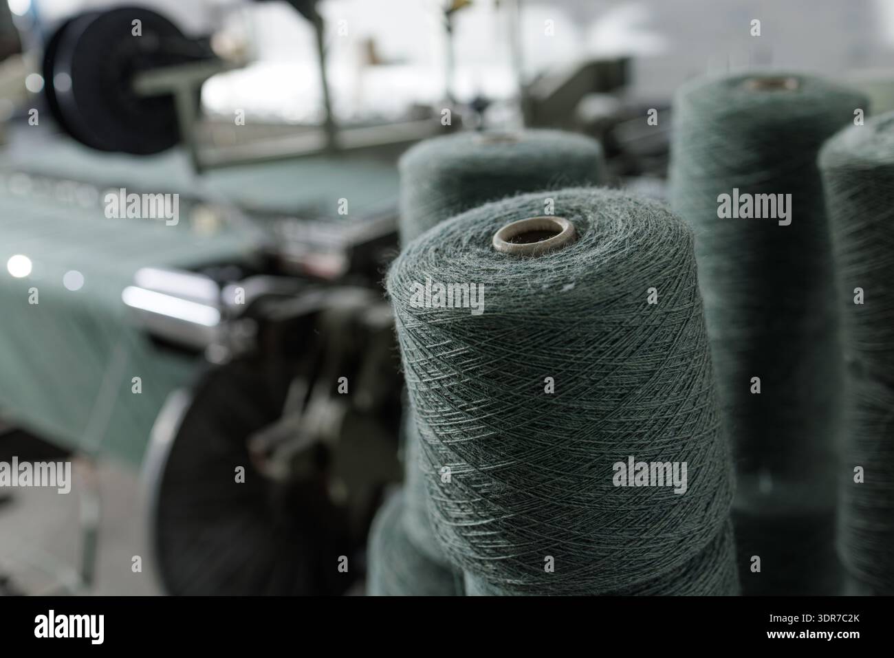 Nahaufnahme von Garnspulen, die auf einer Webmaschine in der Textilfabrik montiert sind, ideal für die Fertigung, die Lieferkette und das industrielle Produktionsmarketing. Stockfoto