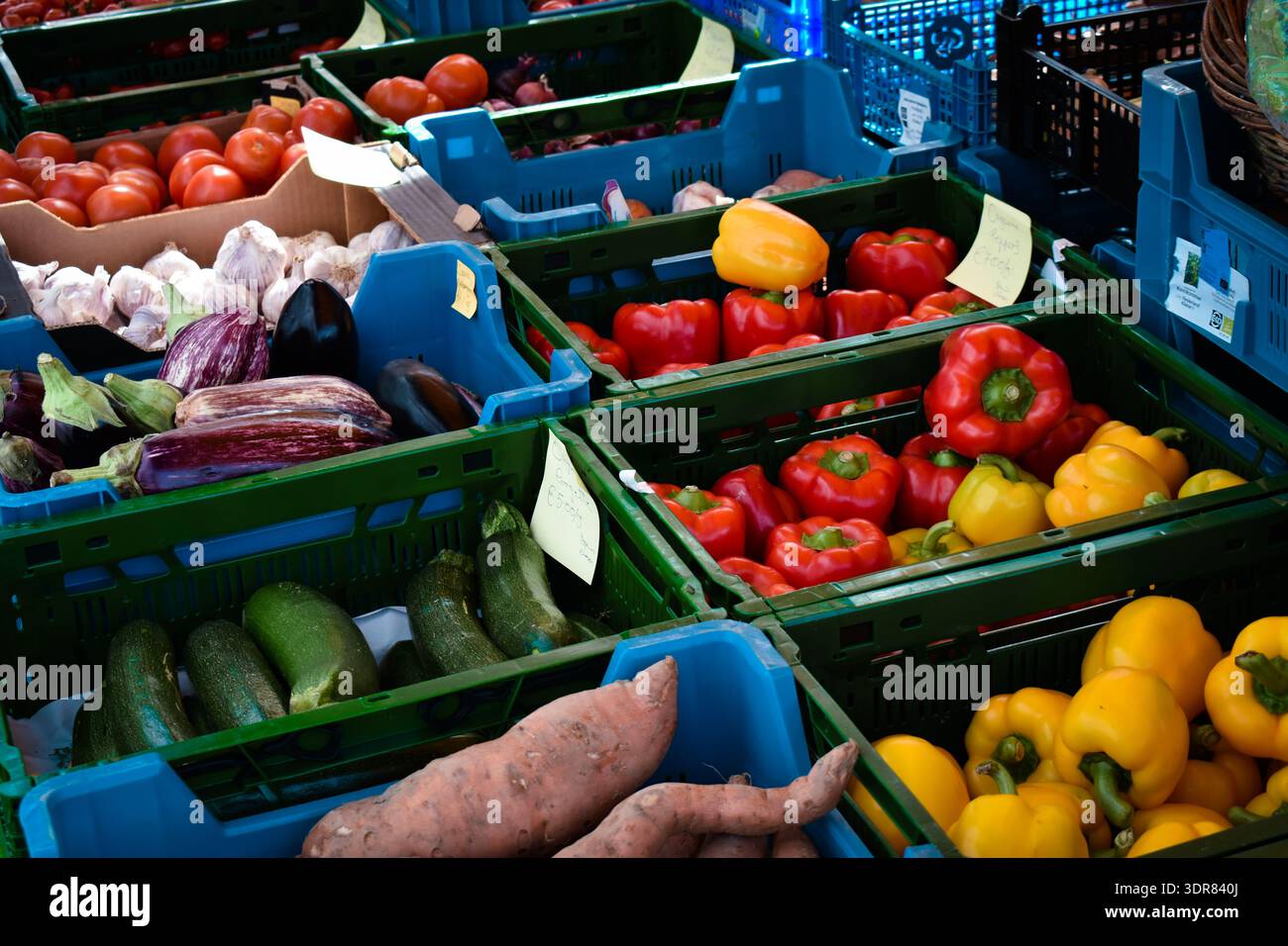 Buntes Gemüse in gestapelten Kunststoffkisten auf einem Markt im Freien Stockfoto
