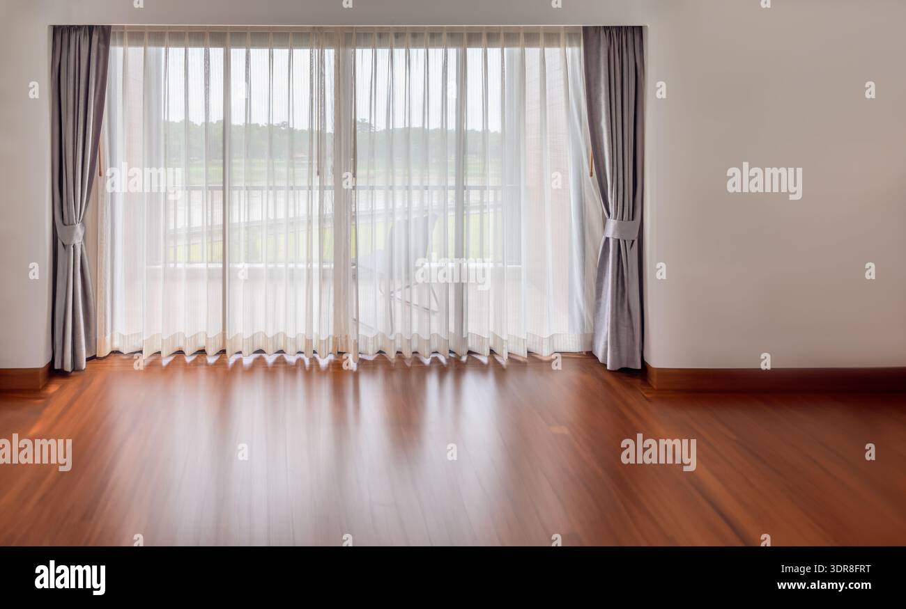 Innenraum des leeren Wohnzimmers mit großen hellen Fenstern und weißen Vorhängen in leerem Zimmer Stockfoto