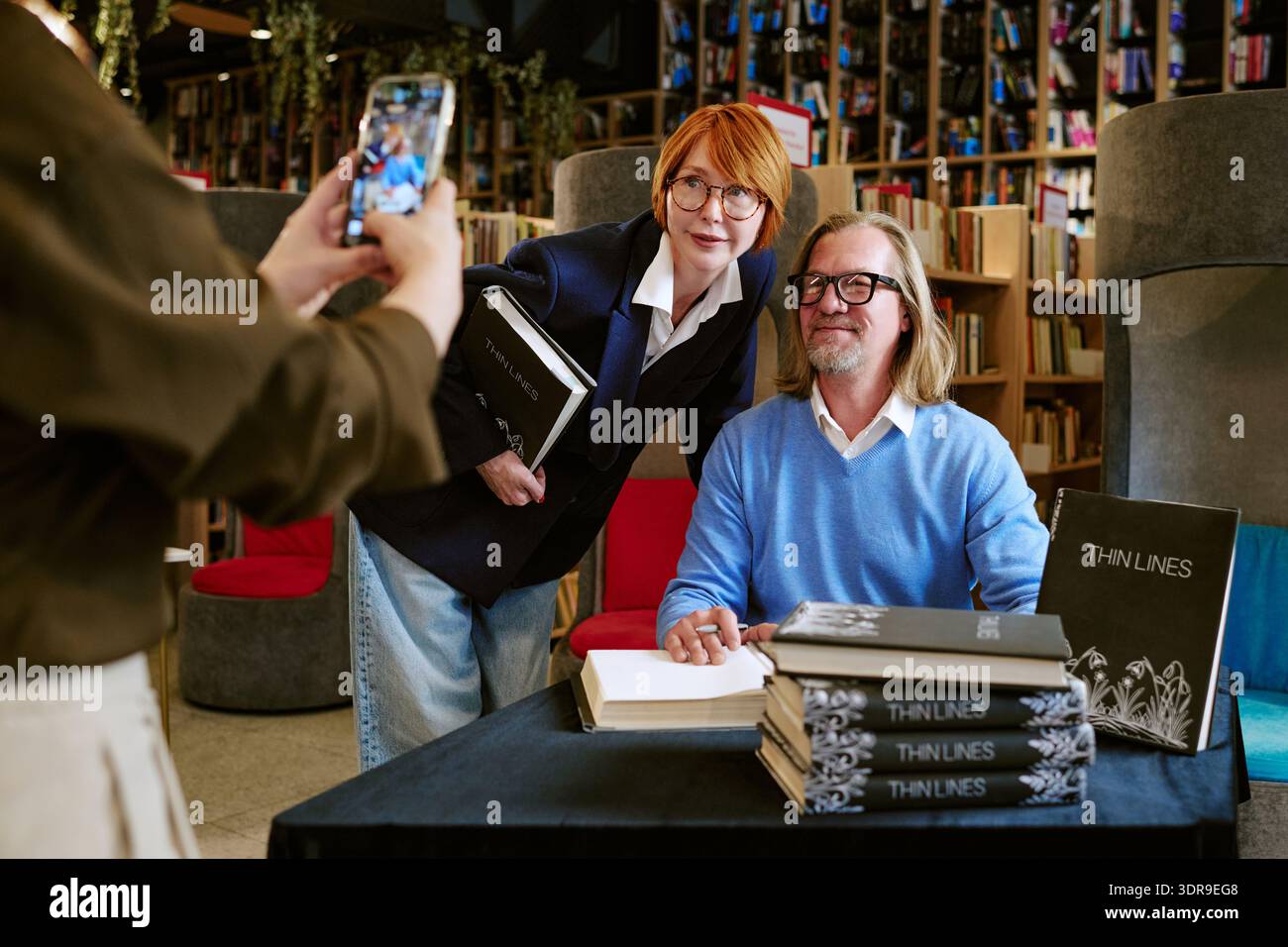 Kaukasischer Mann mittleren Alters unterschreibt Buch mit kaukasischer Frau mittleren Alters posiert Stockfoto
