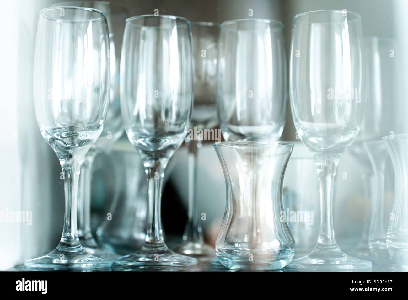 Gläser hinter einer Glasvitrine, die elegante transparente Glaswaren in den Regalen präsentiert. Das klare Material erzeugt ein schönes Licht Stockfoto