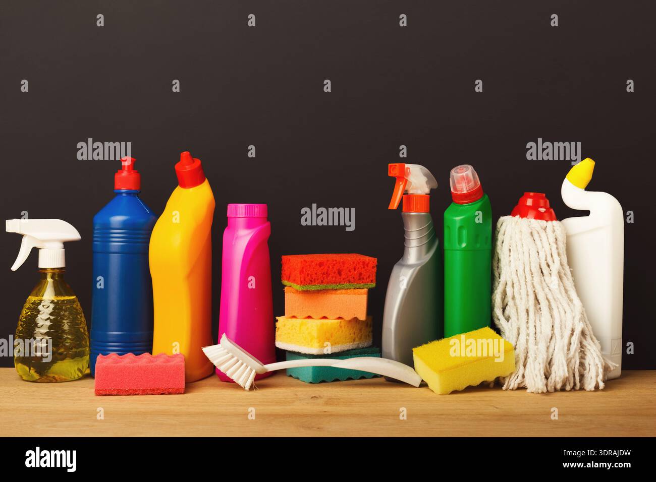 Reinigungszubehör und -Werkzeuge in einer farbenfrohen Sammlung auf einer Holzoberfläche angeordnet Stockfoto