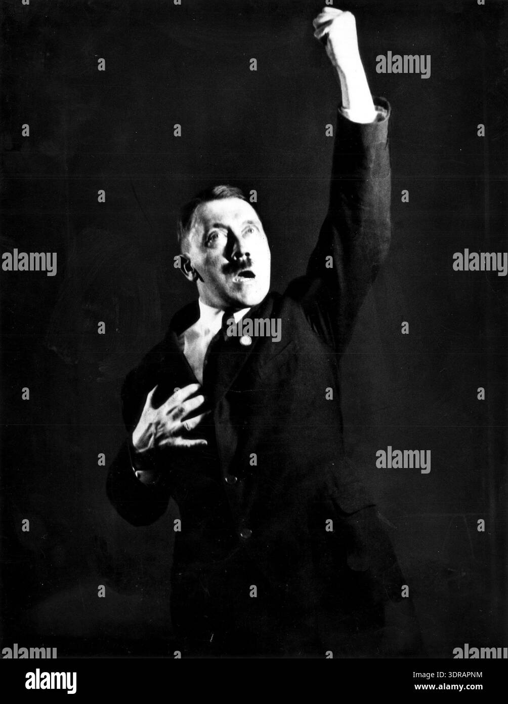 Dieses Foto, das zwischen 1925 und 1930 von Heinrich Hoffmann aufgenommen wurde, zeigt Adolf Hitler, der für die Kamera praktiziert. Das Bild ist ein abgeschnittener Abschnitt einer größeren Szene, einschließlich eines Phonographen, der eine seiner Reden spielt. Hitler wies Hoffmann an, die erhaltenen negative zu zerstören. Das Foto gibt Einblicke in die frühe fotografische Dokumentation, die Inszenierung für Propaganda und den Medieneinsatz in Weimar. Stockfoto