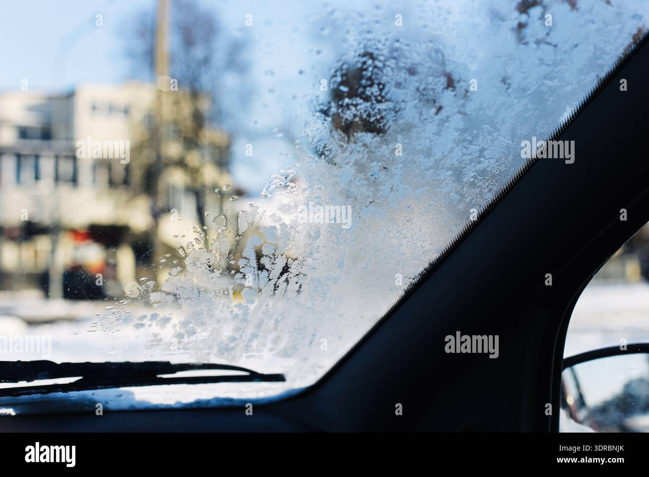 Gefrorene Windschutzscheibe am Wintermorgen. Eis und Kondenswasser an der Fahrzeugscheibe. Transportkonzept bei kaltem Wetter im Freien. Stockfoto