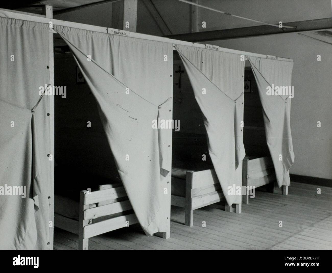 Dieses Foto zeigt den gemeinsamen Schlafsaal des Abdij van Achel, auch Achelse Kluis genannt, in Belgien am 11. Juli 1946. Der Raum verfügt über einfache, strenge Betten, die in Reihen angeordnet sind und das Leben der Trappisten widerspiegeln, in dem Essen, Lernen, Beten und Schlafen gemeinschaftlich sind. Das Bild veranschaulicht die klösterliche Betonung auf Einfachheit, gemeinsame Wohnräume und disziplinierte tägliche Routinen innerhalb der Abtei. Das Arrangement des Schlafsaals demonstriert das trappistische Prinzip des kollektiven und minimalistischen Lebensstils. Stockfoto