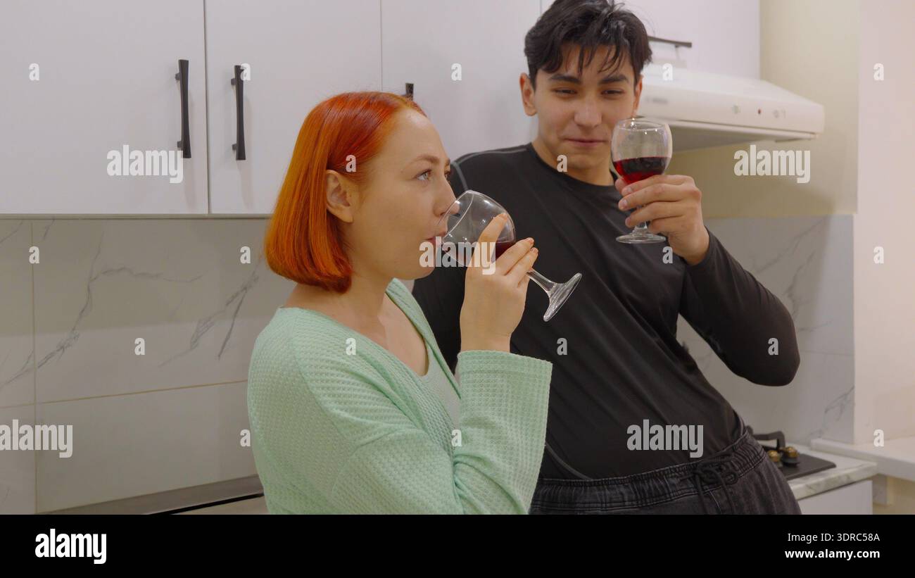 Ein junges Paar trinkt zusammen Wein in einer modernen Küche Stockfoto