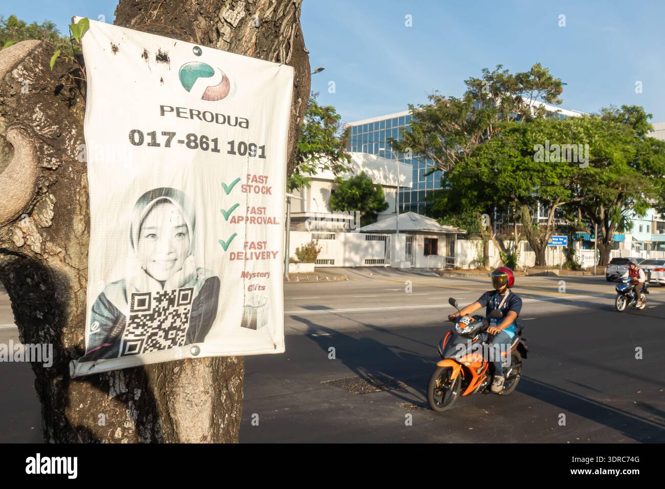 Werbebanner für Perodua-Autoverkäufe, die an einem Baum mit qr-Code angebracht sind, fördern schnellen Service, Lieferung und Genehmigung für den Kauf von Fahrzeugen. Stockfoto