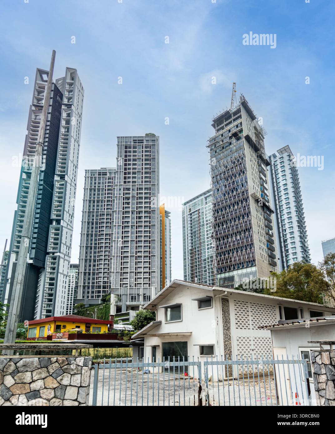 Kontrast zwischen traditioneller, flacher Architektur und moderner Hochhausentwicklung in einer dichten städtischen Umgebung, Kuala Lumpur, Malaysia Stockfoto