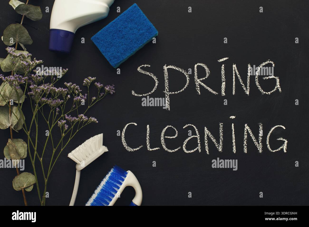 Frühjahrsreinigungswerkzeuge und -Materialien, die auf einer dunklen Oberfläche angeordnet sind, für Organisations- und Reinigungsaufgaben Stockfoto