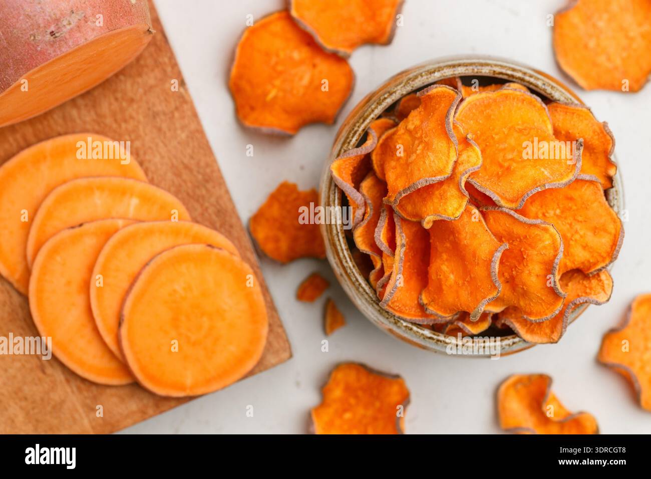 Gesunde Bio Süßkartoffelchips in einer Schüssel und frische Süßkartoffeln Stockfoto