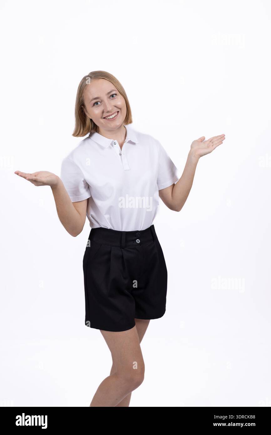 Eine junge Frau in weißem Hemd, die im Studio mit den Schultern zuckt Stockfoto
