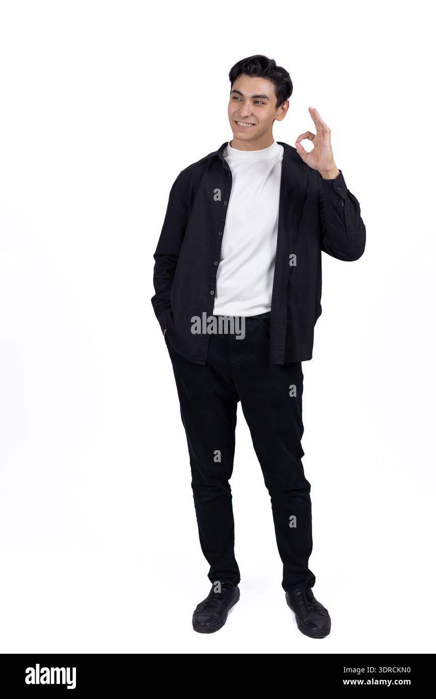 Junger Mann in schwarzem Hemd, der im Studio zur Seite zeigt Stockfoto