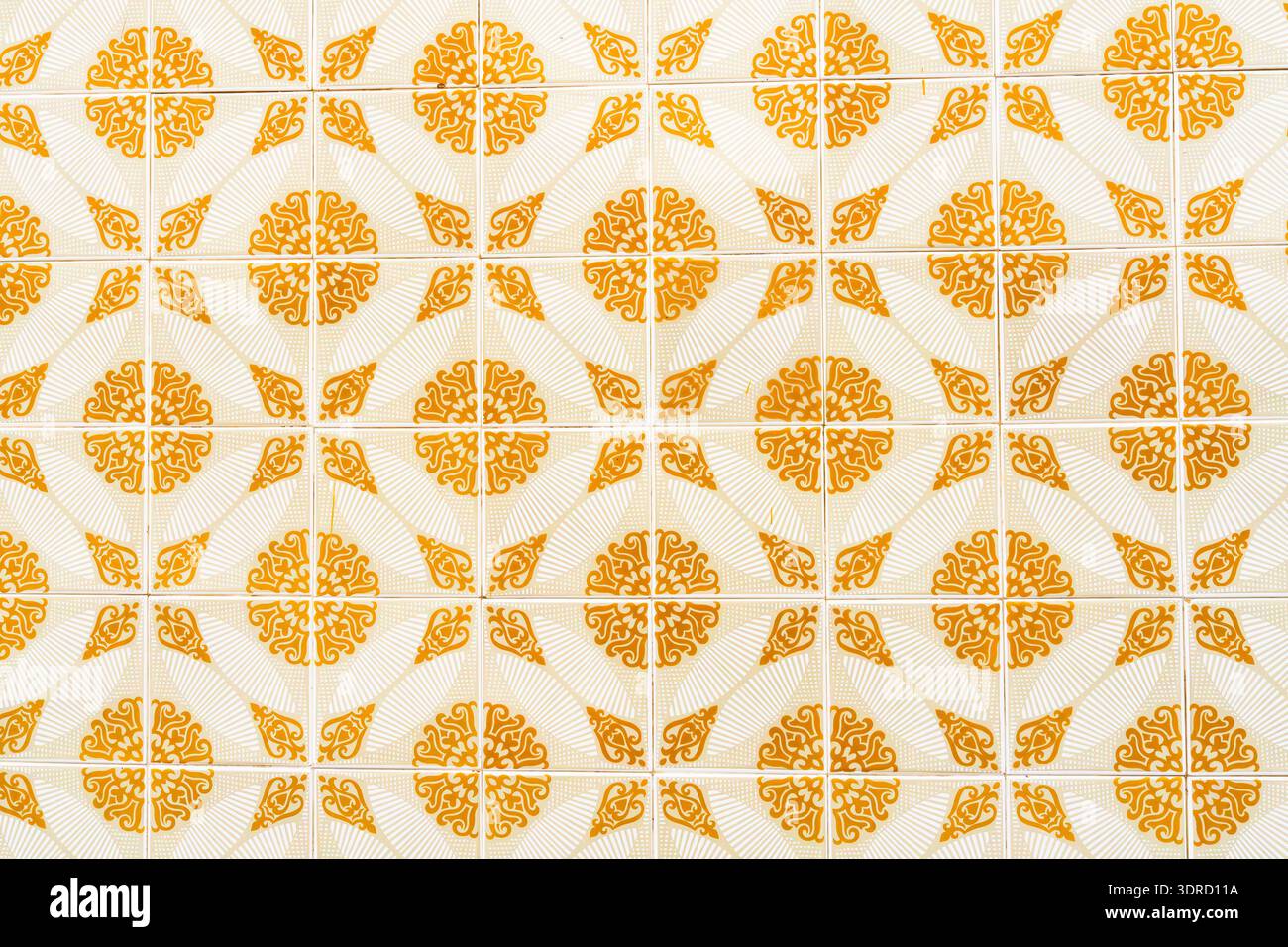 Sich wiederholendes orangenes Blumen- und geometrisches Motiv auf Retro-Keramikfliesen. Stockfoto