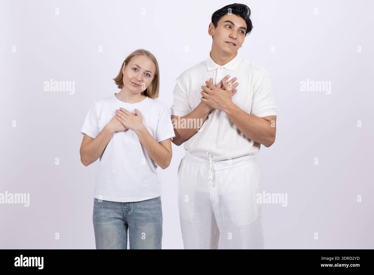Ein junges Paar in weißen T-Shirts, die mit den Händen Herzform machen Stockfoto