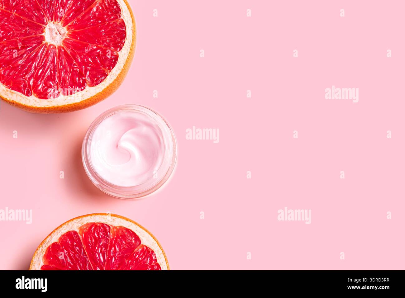Rosafarbener Creme-Feuchtigkeitsbehälter und Grapefruit-Zitrusscheiben Stockfoto