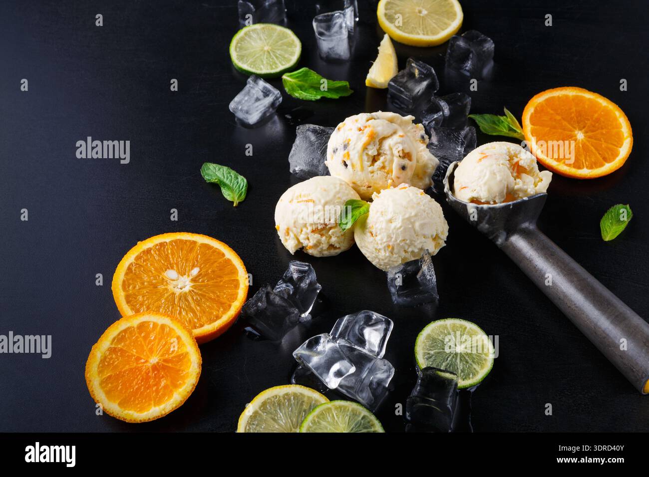 Verschiedene Früchte und Eiskugeln auf einem schwarzen Tisch Stockfoto
