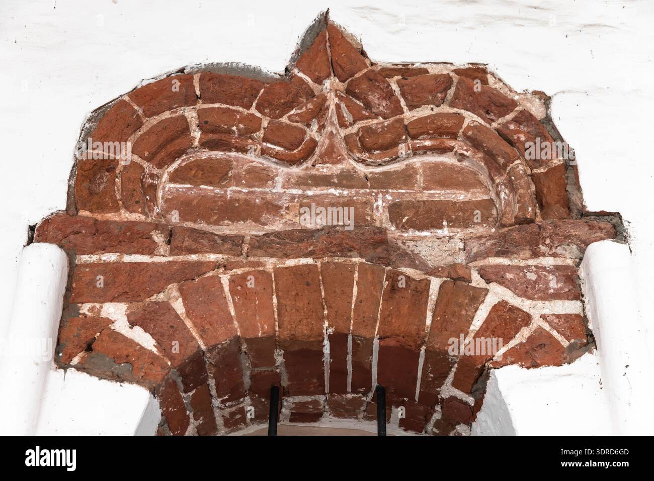 Historischer dekorativer roter Backsteinbogen mit detaillierten Mauerwerk- und Mörtelmustern in weißen Gipswänden des Kremls von Rostow Weliky Stockfoto