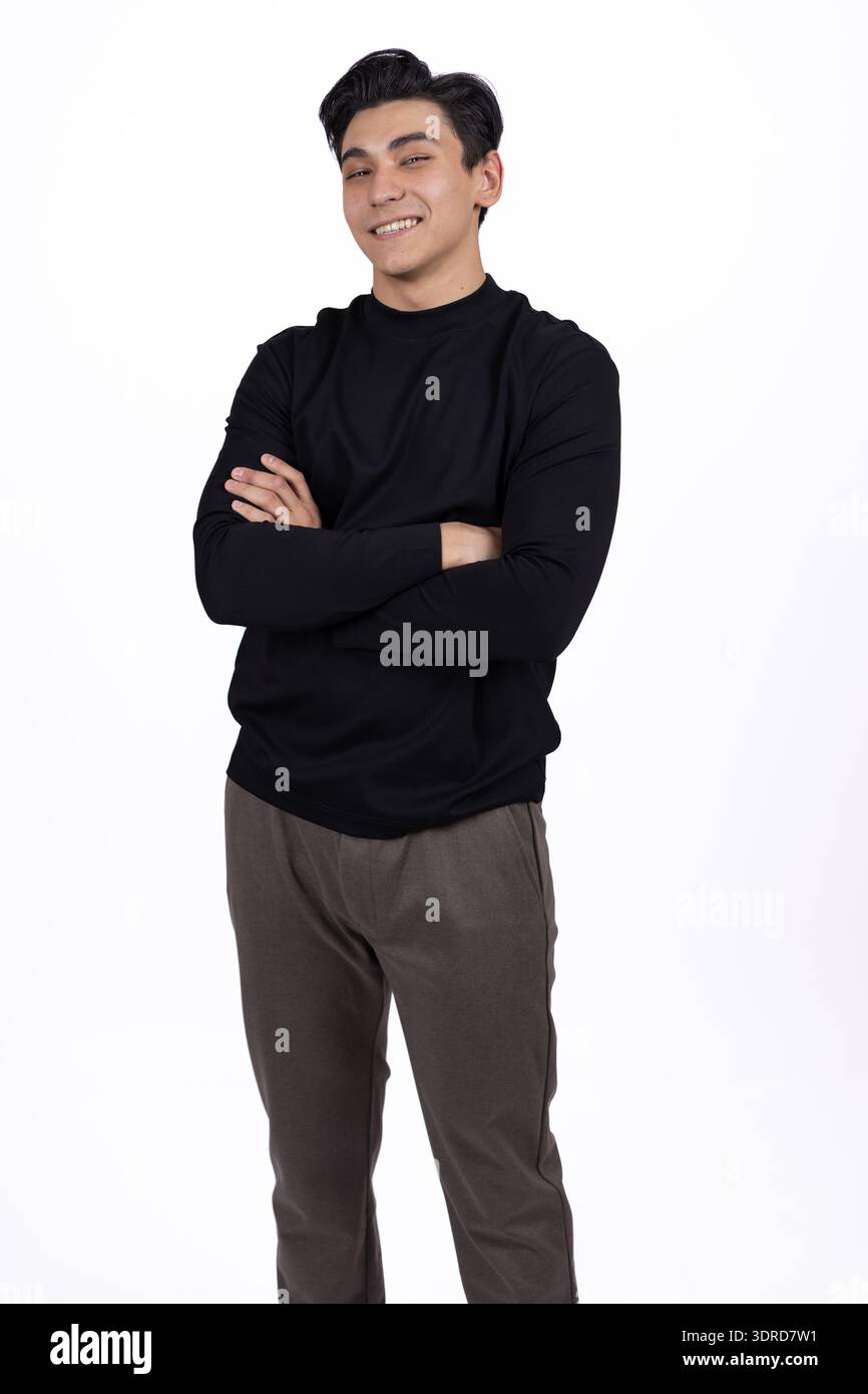Mann im schwarzen T-Shirt posiert mit überkreuzten Armen im Studio Stockfoto