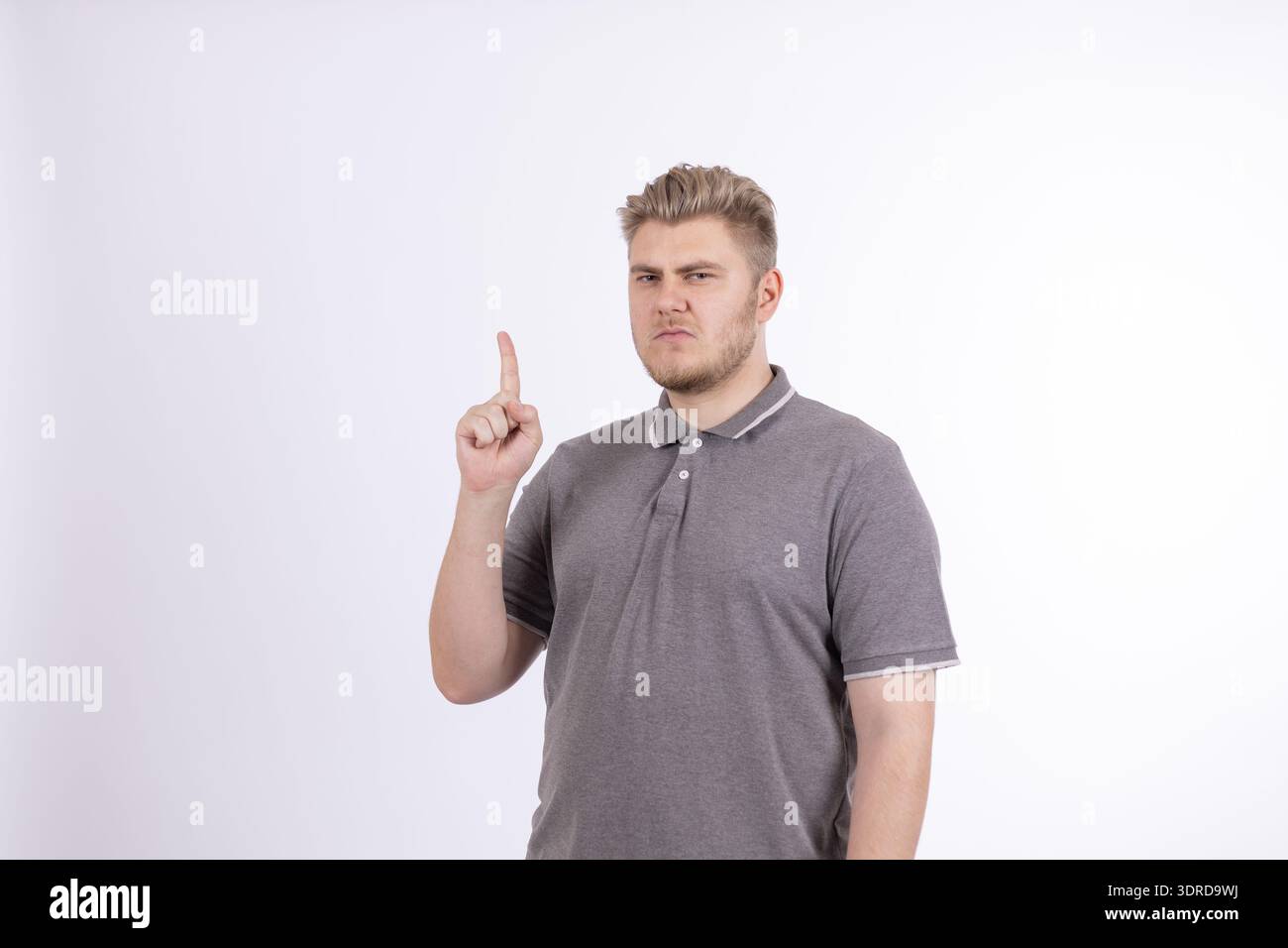 Mann in grauem T-Shirt, der mit einem Finger nach oben zeigt Stockfoto