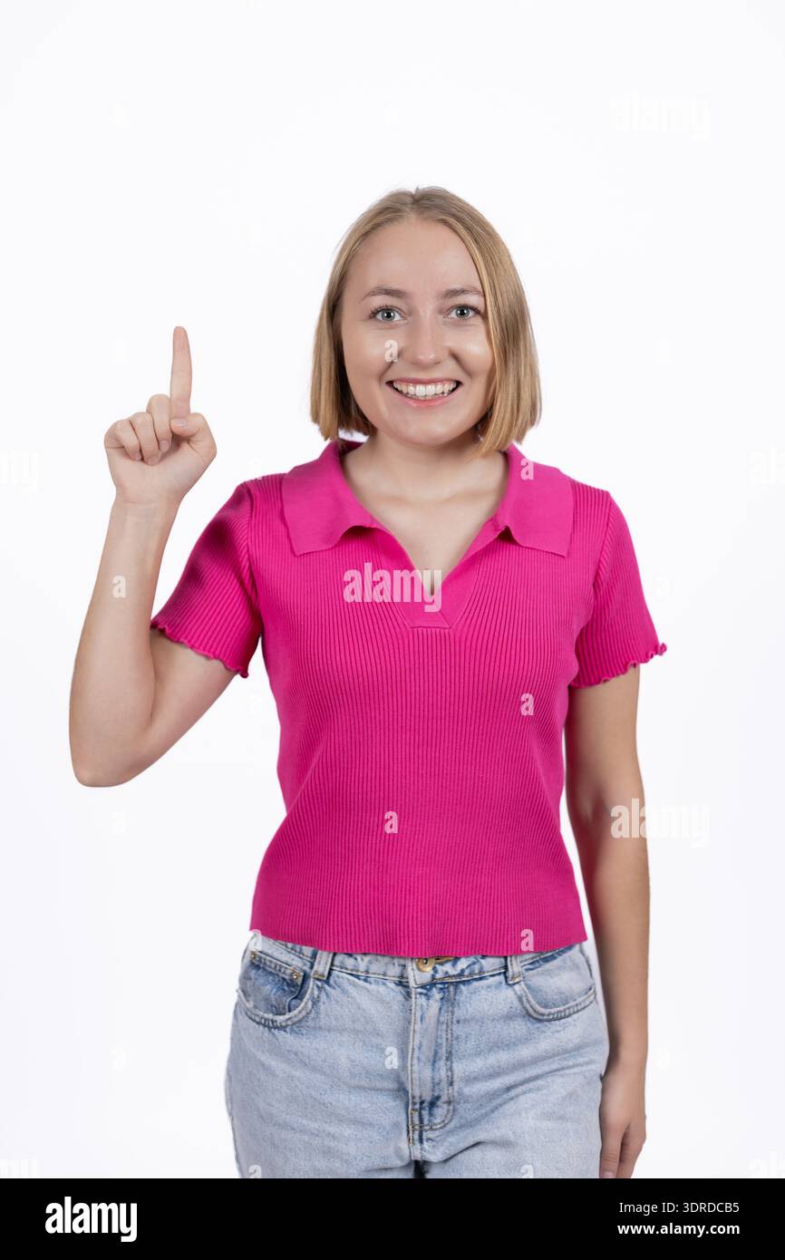 Junge Frau in rosa T-Shirt, die mit einem Finger nach oben zeigt Stockfoto