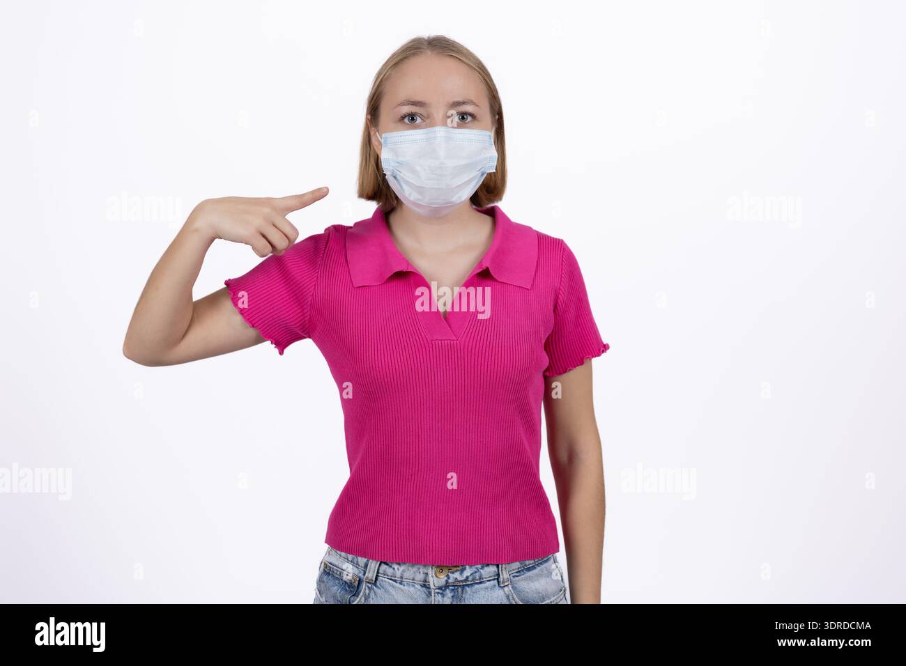 Weibliche Person in rosa T-Shirt, die im Studio auf sich zeigt Stockfoto