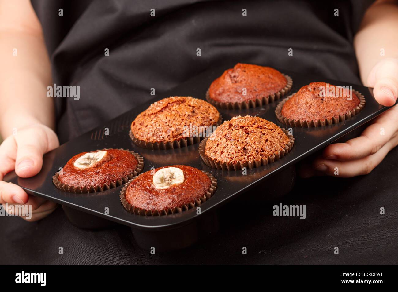Hausgemachte Schokolade, Banane und Karamel Muffins in einer Auflaufform in den Händen. Master Class für junge Konditoren. Dessert für Feinschmecker. Se Stockfoto