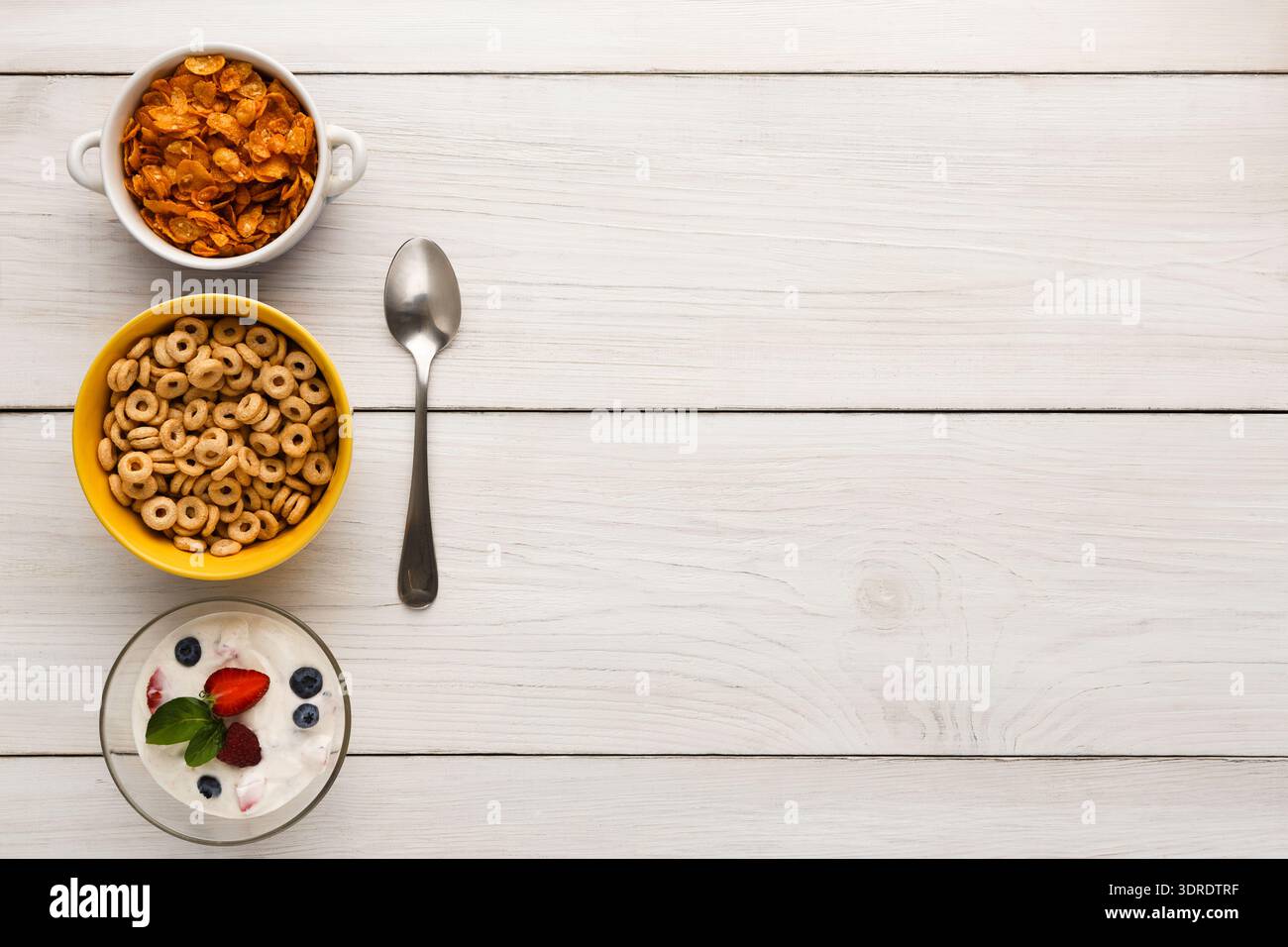 Sammlung von Frühstückszerealien in Schüsseln auf einem Holztisch mit einem Löffel in der Nähe Stockfoto