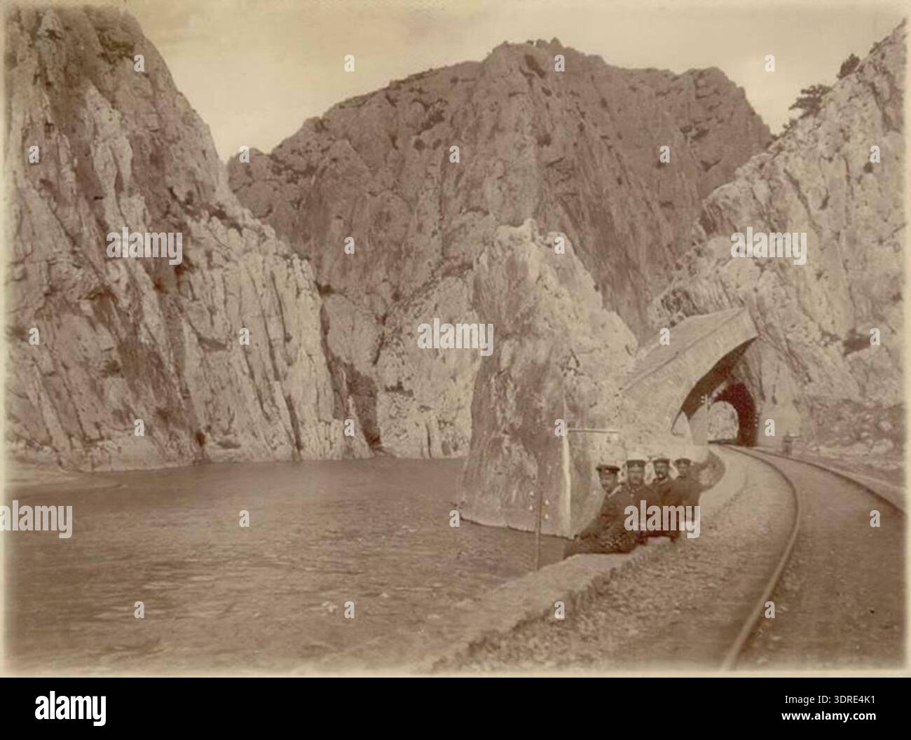 Diese Postkarte aus dem Jahr 1916 zeigt die Eisenbahnstrecke durch den Demir Kapija Canyon in Nordmazedonien entlang des Vardar River. Das Bild zeigt die Wände der Schlucht, die Bahngleise, Brücken und die natürliche Umgebung. Es dokumentiert die Interaktion zwischen dem Balkan und dem Bauwesen des frühen 20. Jahrhunderts und der Landschaft. Die Postkarte dient als historischer Beweis für die Eisenbahninfrastruktur, geografische Merkmale, malerische Ausblicke und technische Lösungen in der Region während dieser Zeit. Stockfoto
