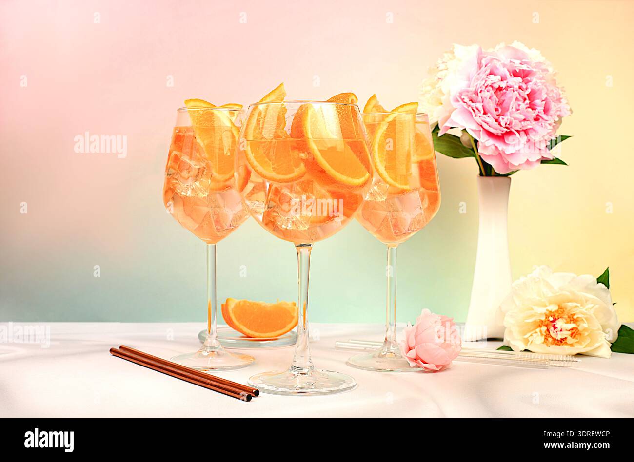 Werbepostkarte für eine Bar oder ein Menü mit festlichen Gläsern Aperol Spritz auf einem hellen, modischen Tisch mit Pfingstrosenblüten und Stockfoto