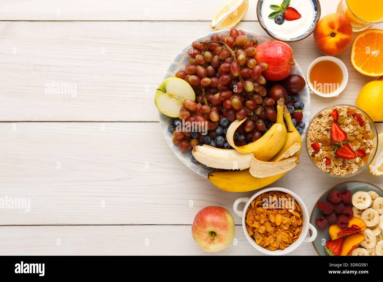 Obst- und Joghurtsammlung in einer Schüssel mit Müsli und Honig auf einem Holztisch Stockfoto