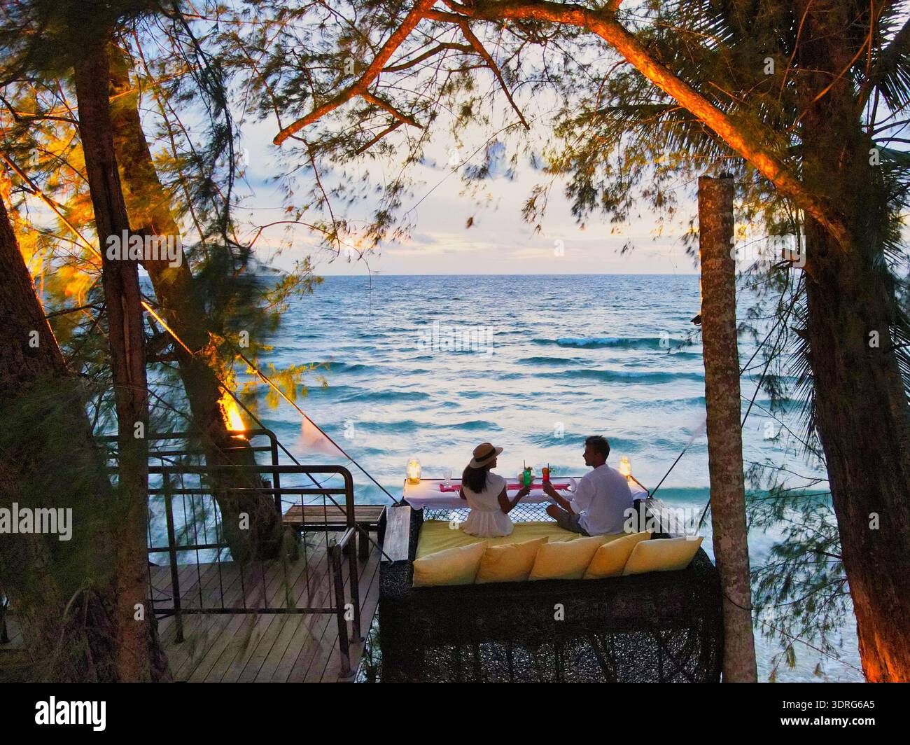 Ein Paar genießt ein romantisches Abendessen bei Sonnenuntergang auf einer Strandterrasse Stockfoto