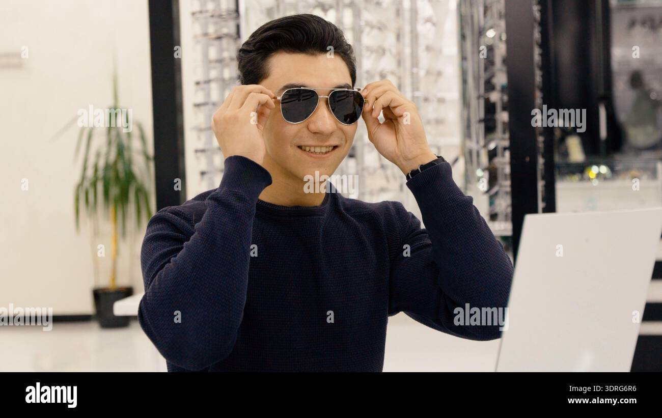 Junger Mann mit Sonnenbrille im Optikgeschäft Stockfoto