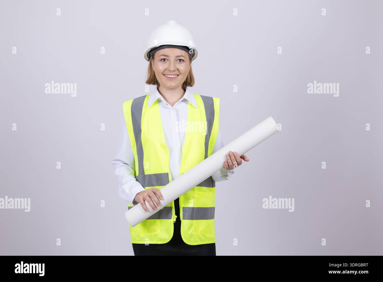Lächelnde Architektin im Helm mit Papierrolle Stockfoto