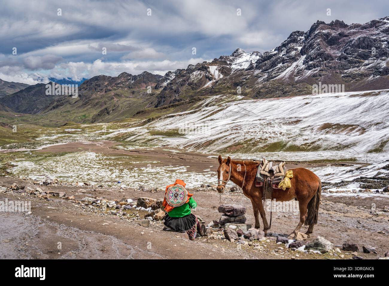 Einheimische peruanische Frau in traditioneller Kleidung ruht neben einem Pferd mit der atemberaubenden Gletscherlandschaft der Vilcanota Bergkette im Hinterland Stockfoto