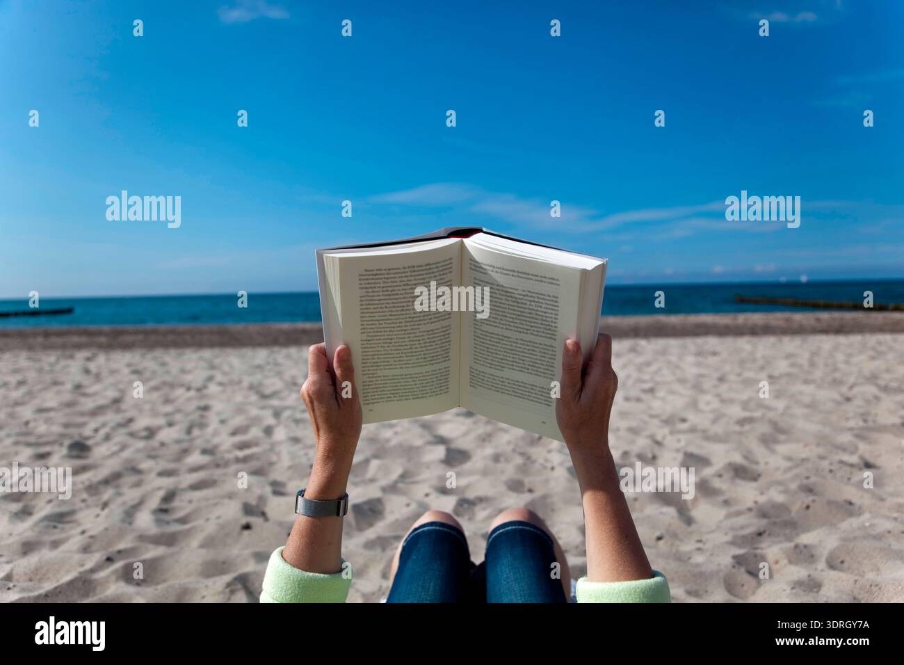 Frau liest ein Buch am Strand Stockfoto