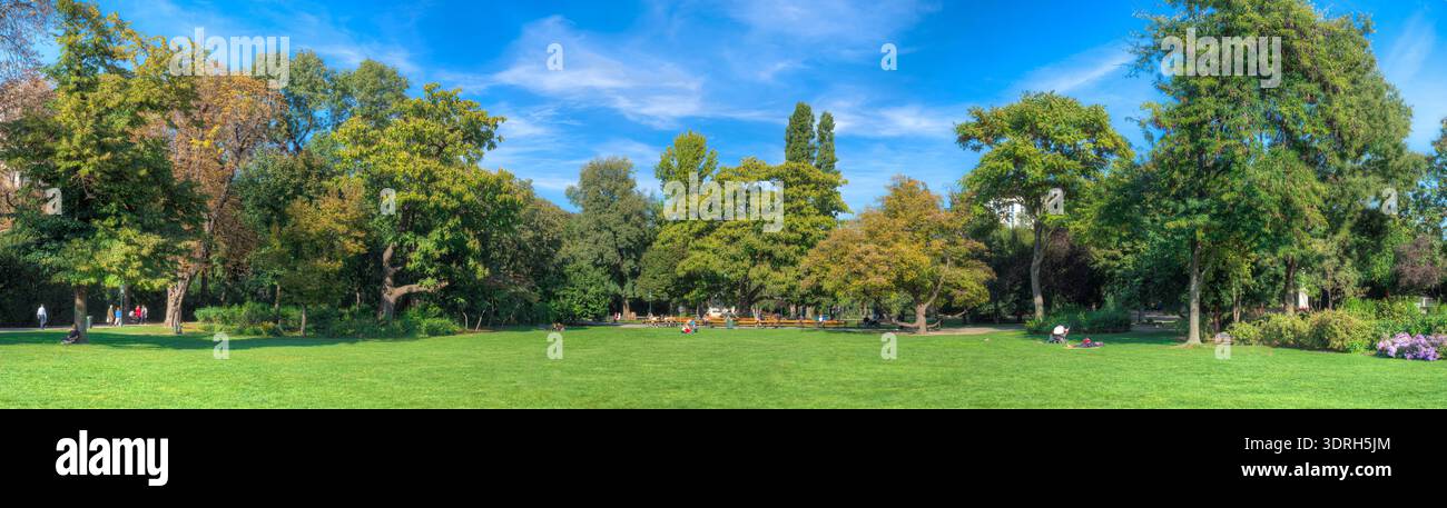 Panorama im Wiener Stadtpark mit Rasenflächen, Laubbäumen und Parkbänken bei schönem, sonnigem Herbstwetter Stockfoto