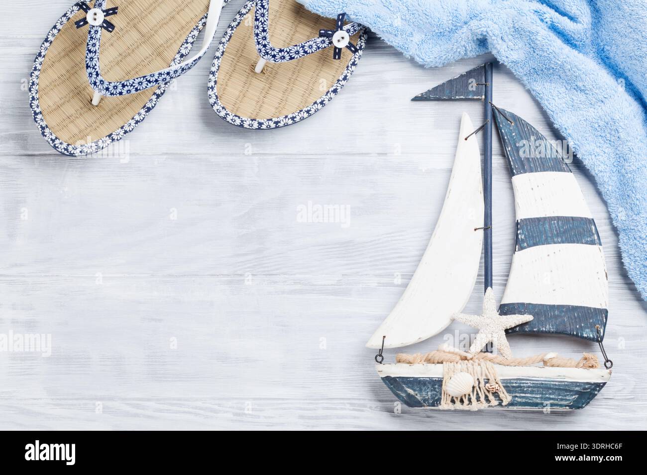 Strand-Accessoires. Flip-Flops, Handtuch und Boot Dekor auf hölzernen Hintergrund. Draufsicht mit Textfreiraum Stockfoto