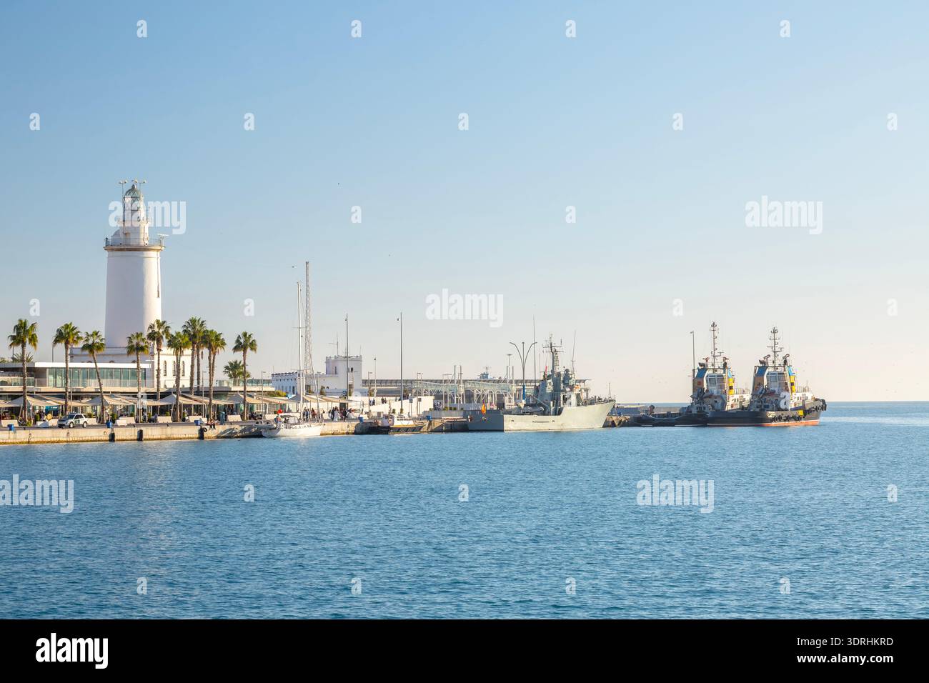 Leuchtturm La Farola de Malaga am Hafeneingang mit Yachten und Seeschiffen, die im Hafen unter klarem blauem Himmel in der Medite angedockt sind Stockfoto