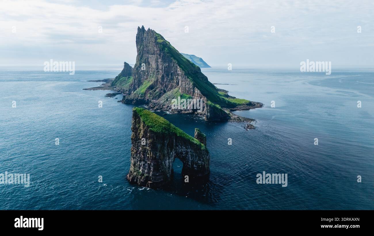 Atemberaubende Klippen erheben sich dramatisch aus dem azurblauen Wasser der Färöer unter klarem Himmel Stockfoto