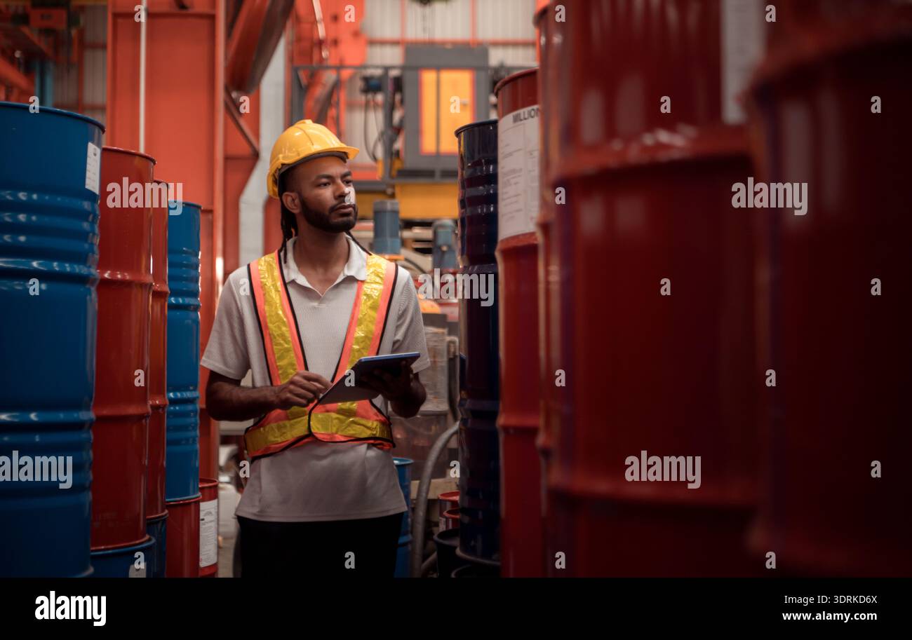Industriearbeiter, der in einem großen Metallrohr in einer Fabrik mit Schutzhelm inspiziert Stockfoto